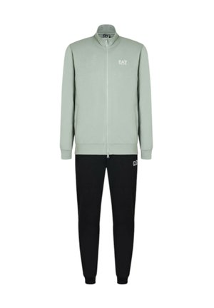 Chaqueta de cremallera verde claro con cuello alto y logo blanco, combinada con joggers negros que presentan un logo. Tejido suave y corte casual.