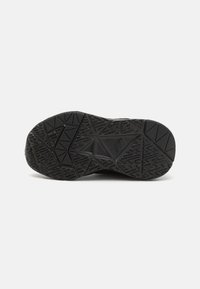 Semelle de chaussure en caoutchouc noir avec surface texturée et motifs géométriques pour l'adhérence. Présente des accents surélevés et des designs de semelle variés.