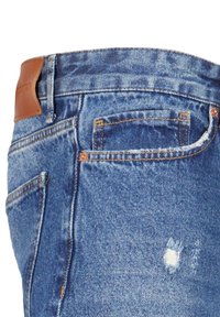 Jeans bleu en denim avec des coutures visibles, une petite déchirure près de la poche, et un patch de marque en cuir marron sur la ceinture.