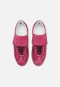 Baskets en suede rose avec un design à lacets plat, languette rembourrée, détails perforés et accents de rose plus foncé.