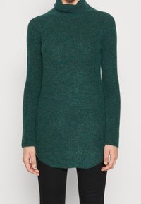 Sweter z golfem w ciemnym odcieniu teal, wykonany z teksturowanej dzianiny, posiada długie rękawy i zaokrąglony dół. Idealny do warstwowego noszenia.
