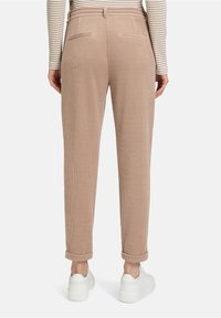 Beżowe spodnie z korduroju o slim fit, z dwoma tylnymi kieszeniami, zrolowanymi mankietami i w zestawie z białymi sneakersami. Teksturowana, prążkowana tkanina.