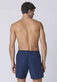 Costumi da bagno blu navy realizzati in tessuto leggero, dotati di una cintura elastica, una tasca posteriore con bottone e senza motivi visibili.