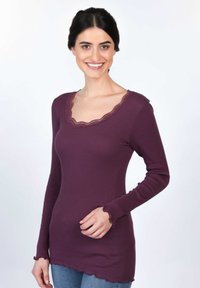 Langärmliges Oberteil aus tiefviolettem Rippstoff, mit einem gewellten Spitzen-Halsausschnitt und -ärmeln sowie einem leicht geschwungenen Saum.
