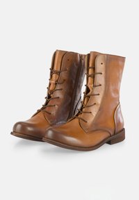 Botas de tobillo de cuero marrón con punta redondeada, cordones en la parte delantera y cremallera lateral. Presentan un acabado suave y un tacón bajo apilado.