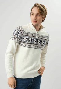 Biała sweter z dzianiny z wzorzonym górnym odcinkiem w granatowe i ciemnoniebieskie geometryczne wzory; zawiera kołnierz z półzapinanym suwakiem.