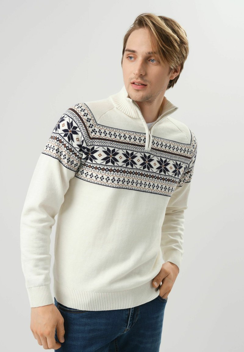 Biała sweter z dzianiny z wzorzonym górnym odcinkiem w granatowe i ciemnoniebieskie geometryczne wzory; zawiera kołnierz z półzapinanym suwakiem.