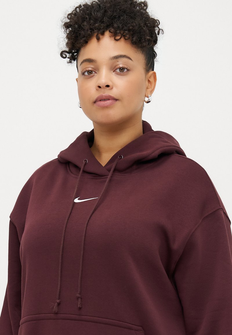 Burgunderfarbener Hoodie mit einer Fronttasche, Kapuze mit Kordelzug und weißem Nike-Logo. Weicher Stoff mit lockerer Passform und strukturierter Oberfläche.