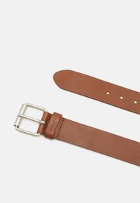 Ceinture en cuir marron avec une texture lisse, boucle en métal argenté et plusieurs trous pour ajustement. Présente un marquage sur la sangle.