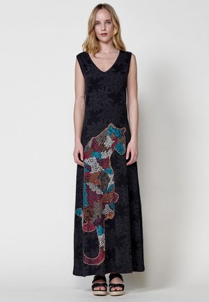 Abito maxi nero con scollatura a V, caratterizzato da un dettagliato ricamo di animali colorati. Texture a motivo floreale su tutta la superficie. Indossato con sandali neri con zeppa.