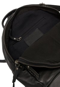 Interieur van een zwarte leren rugzak met een ritsvak en een stoffen voering. Gestructureerd oppervlak met gladde accenten en duurzaam beslag.