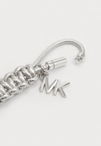 Porte-clés en argent tressé avec une finition métallique élégante et un charm en forme de logo MK suspendu. Texture lisse avec des accents polis.