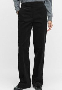 Zwarte corduroy wijde-pijp broek met een gestructureerd oppervlak, met zijzakken en een hoge tailleband, gestyled met een grijze gebreide top.
