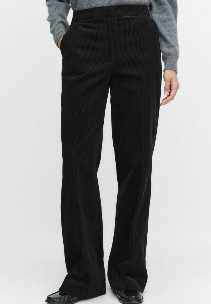Zwarte corduroy wijde-pijp broek met een gestructureerd oppervlak, met zijzakken en een hoge tailleband, gestyled met een grijze gebreide top.