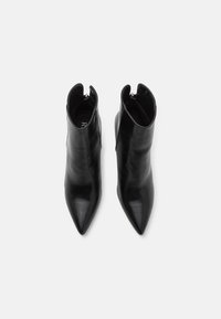 Bocanci negri din piele, până la gleznă, cu vârf ascuțit și închidere prin fermoar la spate. Textură netedă și siluetă elegantă, cu laterale tăiate.