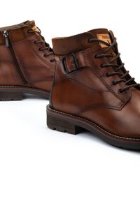 Botas de tobillo de cuero marrón con acentos de ante texturizado, puntera redonda, cordones en la parte delantera, cremallera lateral y costuras en contraste sobre una suela de goma duradera.