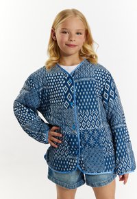Blå mønstret pufferjakke med geometriske og blomsterdesigns. Langærmede, knaplukninger og kontrasterende blå kant.