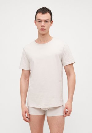 Helle beige T-Shirt mit rundem Ausschnitt und kurzen Ärmeln, aus einem weichen Stoff gefertigt, kombiniert mit passenden hellbeigen Shorts.