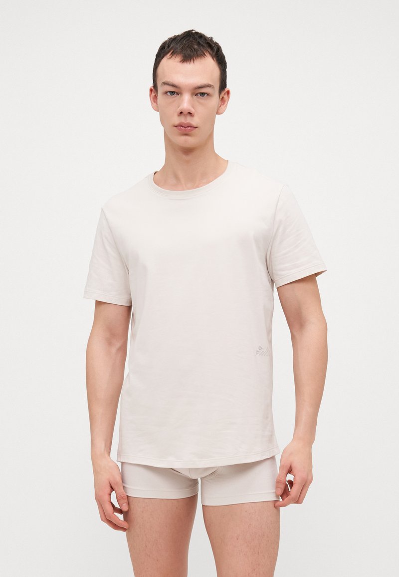 Helle beige T-Shirt mit rundem Ausschnitt und kurzen Ärmeln, aus einem weichen Stoff gefertigt, kombiniert mit passenden hellbeigen Shorts.