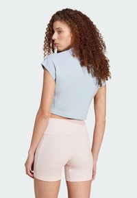 Top corto a maniche corte in tessuto a coste di colore azzurro chiaro con scollatura rotonda, abbinato a pantaloni corti a coste di colore rosa pallido.