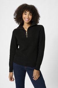 Pull en tricot noir avec zip quart et accessoires en or, présentant une texture côtelée et une coupe décontractée, associé à un jean bleu.