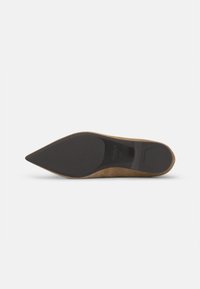 Beige Wildleder-Stiletto-Schuh mit spitzem Zehenbereich und schwarzer Gummisohle. Das Äußere zeichnet sich durch eine glatte Textur und ein eng anliegendes Design aus.