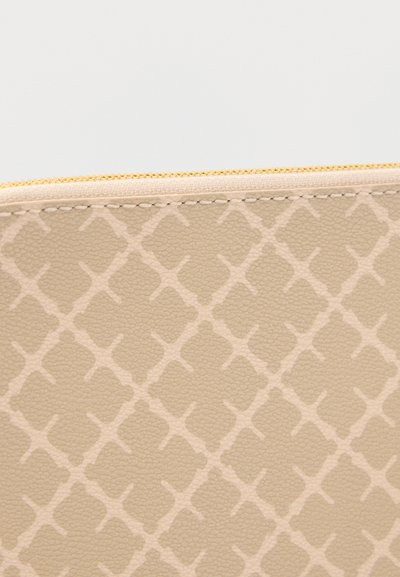 Μπεζ υφασμάτινο τσαντάκι με ανοιχτό γεωμετρικό διαμάντι μοτίβο και εμφανή ραφές κοντά σε χρυσλό φερμουάρ.