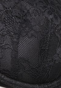Black lace bra featuring floral patterns, textured mesh fabric, smooth structure, and seamless edges for a refined finish.