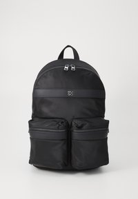 Sac à dos en nylon noir avec un sommet arrondi, deux poches avant zippées et une bande horizontale estampillée avec le logo "HUGO". Fini texturé.