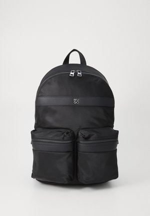 Black nylon backpack with an arching top, two zippered front pockets, and a branded horizontal strip featuring the logo "HUGO." Textured finish.