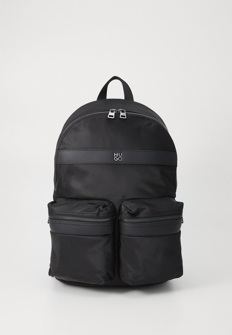 Sac à dos en nylon noir avec un sommet arrondi, deux poches avant zippées et une bande horizontale estampillée avec le logo "HUGO". Fini texturé.