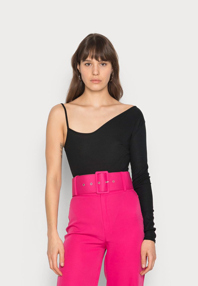 Bodysuit preto canelado com uma manga longa, combinado com calças cor-de-rosa de cintura alta com um cinto largo e detalhe de fivela grande.