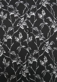Tissu noir avec un motif floral blanc et une vigne épineuse, et des boutons noirs alignés verticalement au centre.