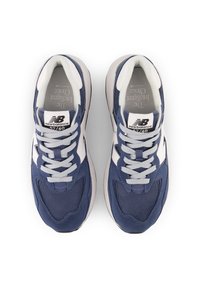 Navy blue athletic shoes with mesh and suede upper, white accents, textured sole, and grey laces. Features New Balance branding on tongue.