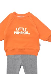 Orangener Sweatshirt mit dem Aufdruck "KLEINE KÜRBIS", kombiniert mit grauen gerippten Leggings. Baumwollmischung, gerippte Bündchen, weiche Textur.