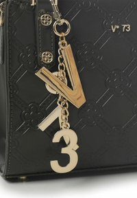 Zwarte synthetische handtas met een reliëf bloemenpatroon, voorzien van accenten van goudkleurig metaal en decoratieve chunky bedels "V" en "3" aan een ketting.