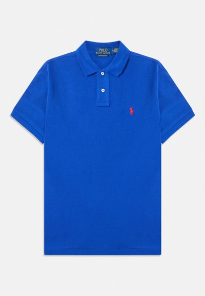 Zils kokvilnas polo krekls ar klasisku apkakli, divu pogu aizdares, īsām piedurknēm un sarkanu izšūtu emblēmu uz kreisā krūšu.