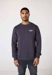 Mørkegrå sweatshirt med rund hals og ribbede manchetter. Har hvid broderet tekst på brystet. Blød stofstruktur.