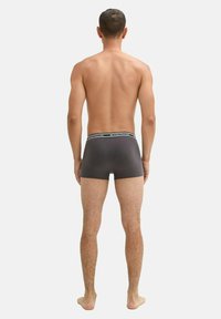 Szürke szövet boxer alsónadrág fekete derékkal, a márkanevével. Rövid lábszárú design, puha tapintás és szoros illeszkedés.