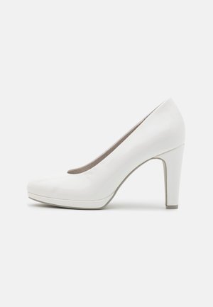 Hvide patenterede læderpumps med høj hæl og rund tå, glat tekstur og en hælhøjde på 10 cm, der har en kontrasterende beige inderside.