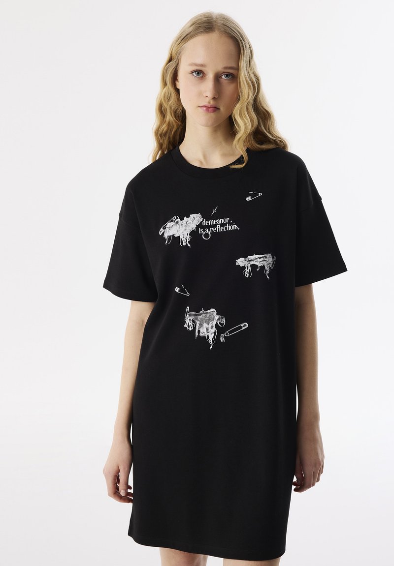 Zwart katoenen t-shirtjurk met korte mouwen, voorzien van witte grafische prints van dieren en tekst, relaxed fit, knielange ontwerp.