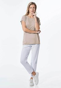 Beige t-shirt met opgerolde mouwen, gecombineerd met witte broek en witte sneakers. Slim fit en gladde katoen stof, minimalistisch ontwerp.