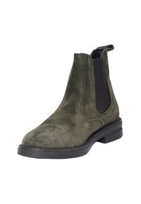 Stivaletto in suede verde oliva con pannelli laterali elastici, punta arrotondata e suola in gomma nera. Dettaglio di cucitura minimale lungo le cuciture.