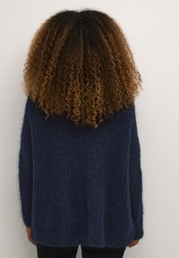 Jūras spēku stila pārspīlēts džemperis ar teksturētu, pūkainu adījumu. Dziļš V-veida kakls, nolaistas plecu daļas un garas piedurknes. Vienkāršs, vienkrāsains dizains.