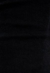 Tejido de mezclilla negro con una textura suave y un ligero estiramiento, mostrando una vista cercana del tejido y del tono oscuro.
