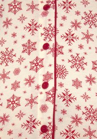 Il tessuto con motivo di fiocchi di neve rosso e bianco presenta bottoni e rifiniture rosso scuro lungo la parte anteriore, creando un design accogliente e festoso.