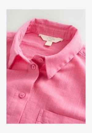 Rozā linu krekls ar apkakli un saskaņotām rozā pogām. Audumam ir tekstūra, un priekšpusē ir krūšu kabata. Etiķete norāda, ka tas ir no lina.