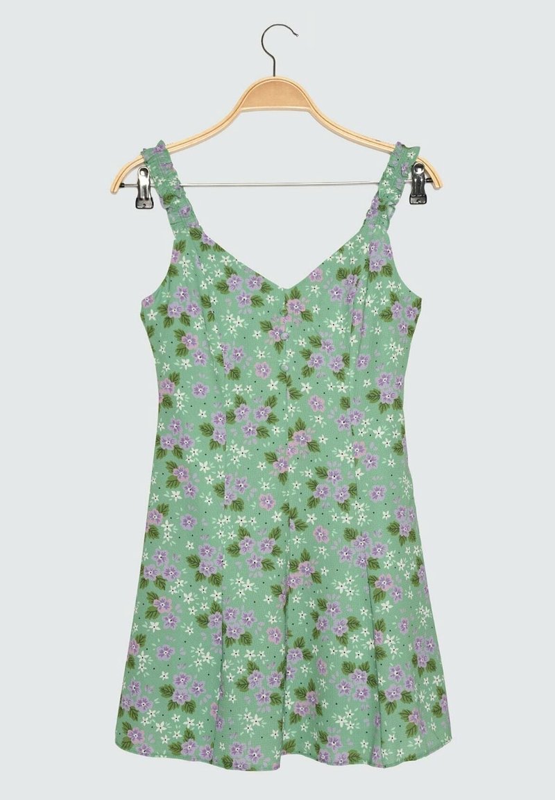 Robe florale en tissu vert, ornée de fleurs violettes et d'accents blancs. Bretelles spaghetti, décolleté en V et jupe évasée.