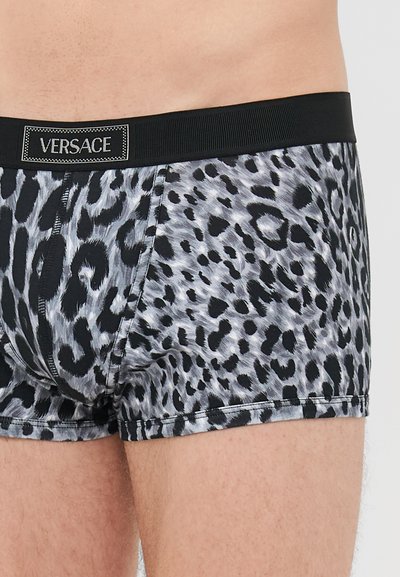 Férfi szürke és fekete leopárdmintás boxeralsó fekete derékrésszel, amelyen a Versace logó felvarrás található.