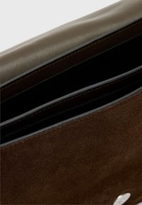 Brun lædertaske med en glat top, tekstureret suede bund og to rum. Har sølvhardware og sort indvendig foring.